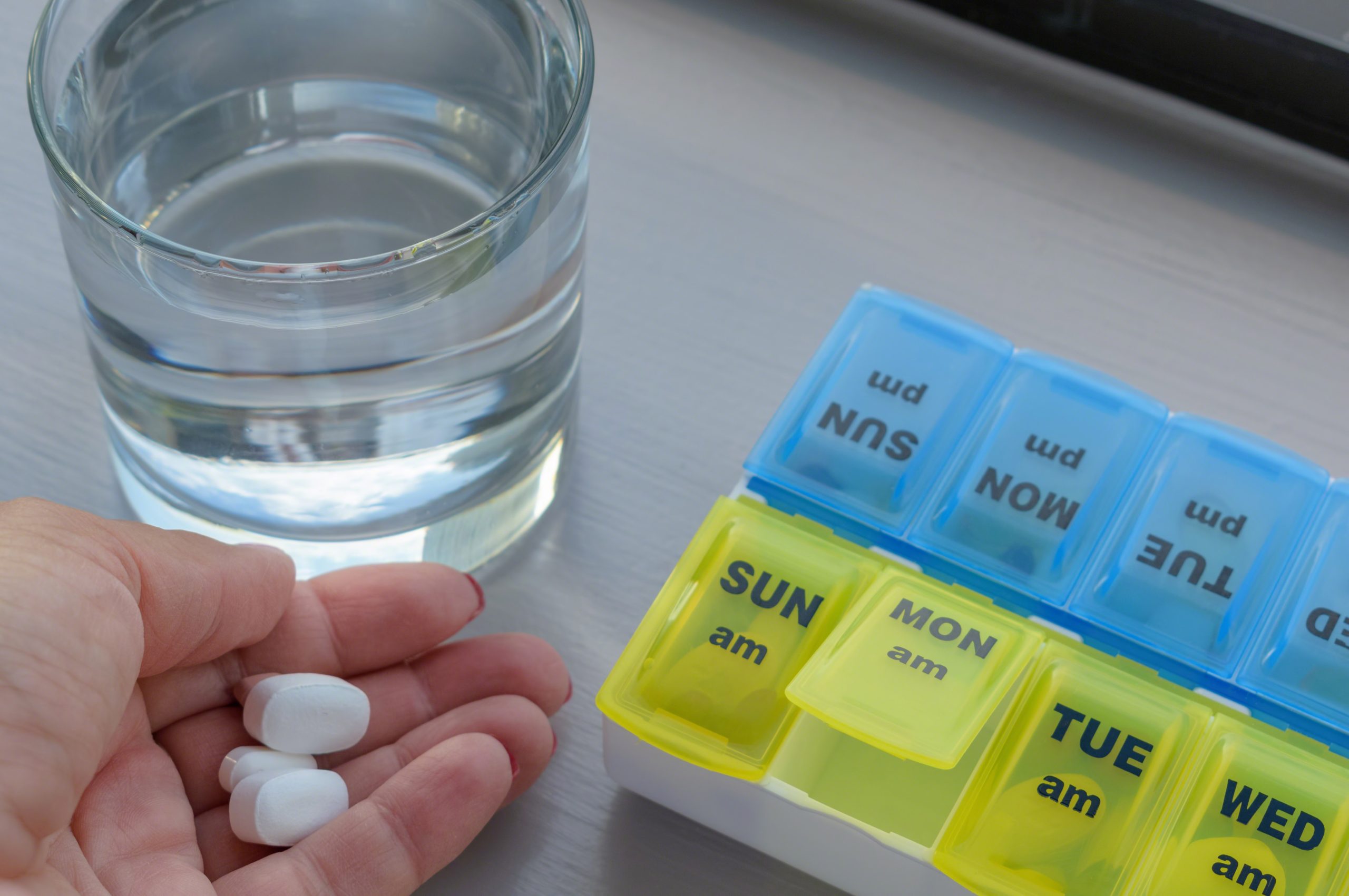 Woman using a pill holder to manage daily medication