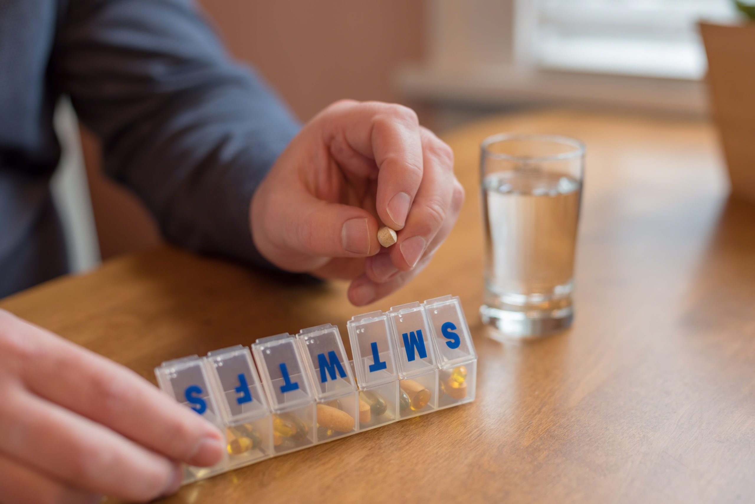 Man filling a pill holder with daily meds, vitamins and supplements